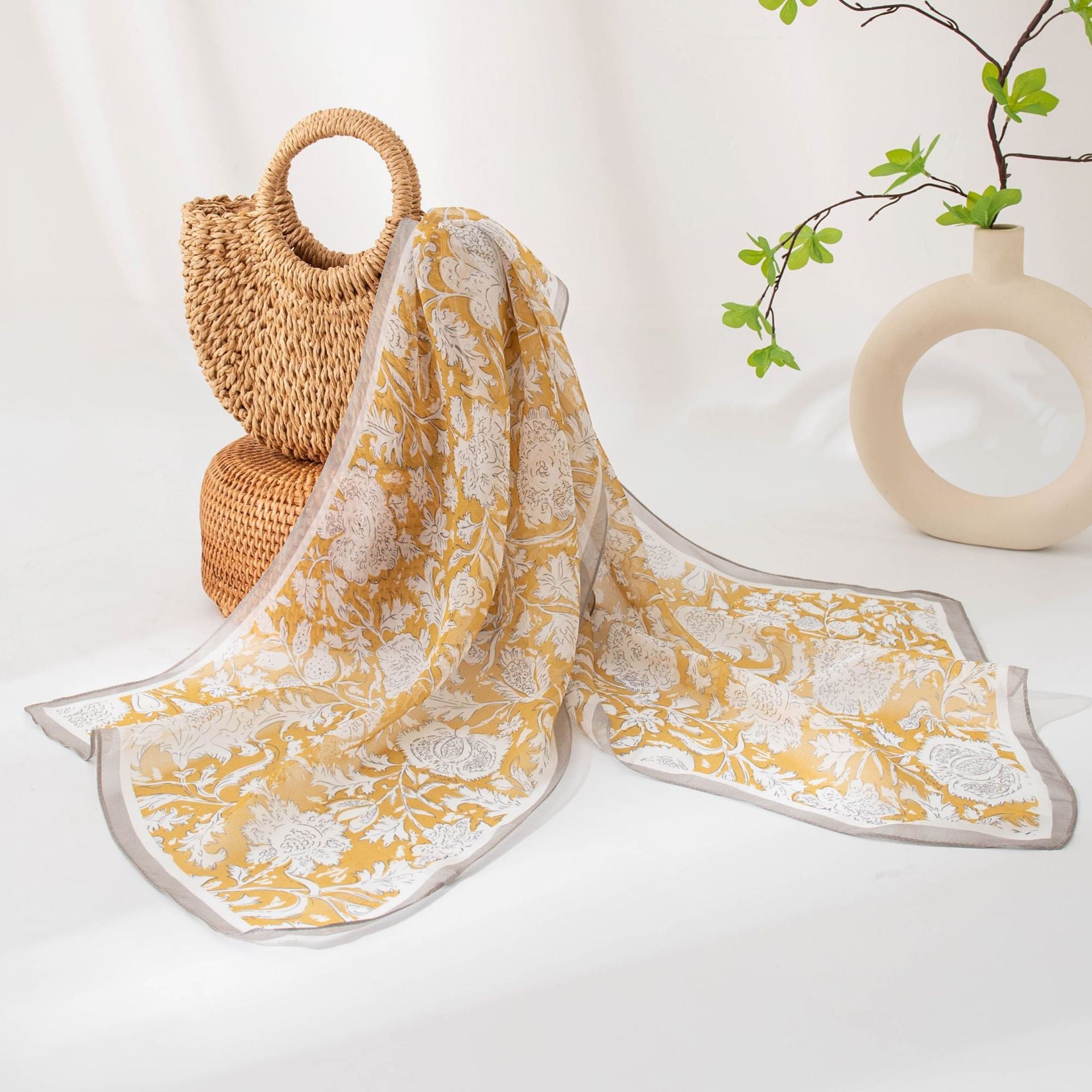 Golden peony printed mulberry silk long scarf styled with a woven bag and sculptural ceramic decor